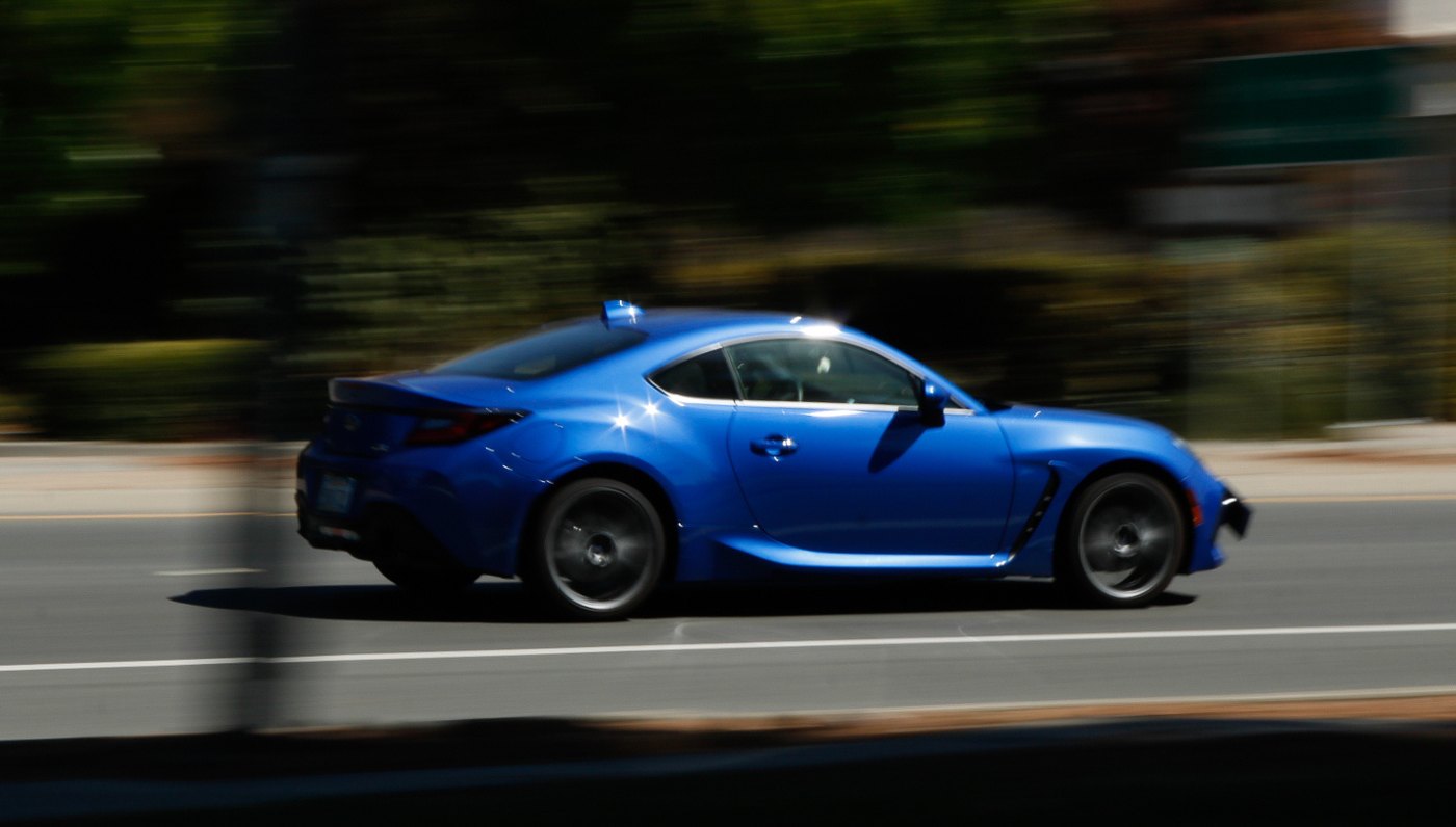 A blue sports car in motion, sharp against a motion-blurred road